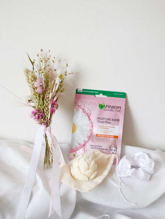 wildflower dried bouquet, with a beauty skincare face mask and a cream lotus mini candle on a white fabric cloth