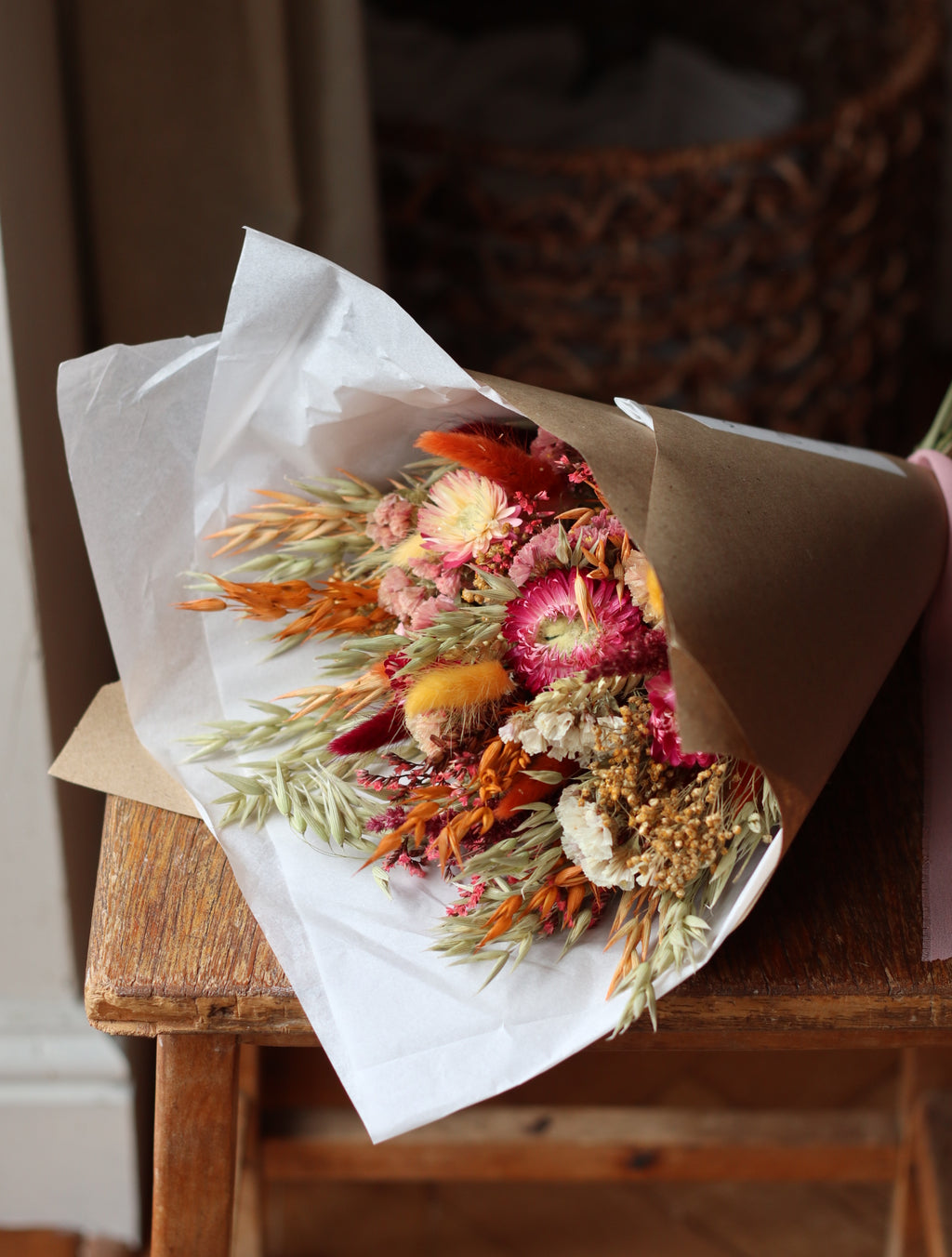 Bouquet of dried flowers wrapped in brown paper on a wooden surface