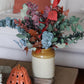 Decorative arrangement of artificial flowers in a vase on a table.