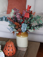 Decorative arrangement of artificial flowers in a vase on a table.