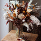 Dried floral arrangement on a wooden chair with a neutral background