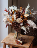 Dried floral arrangement on a wooden chair with a neutral background