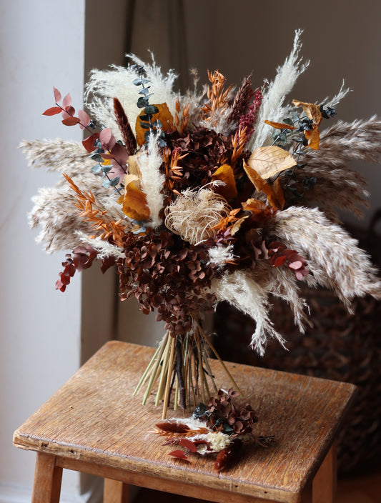 Dried floral arrangement on a wooden chair with a neutral background