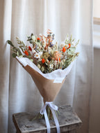 Bouquet of flowers wrapped in brown paper on a wooden surface