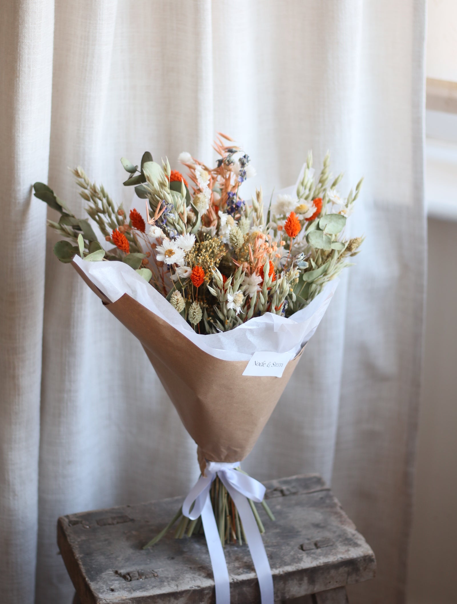 Bouquet of flowers wrapped in brown paper on a wooden surface