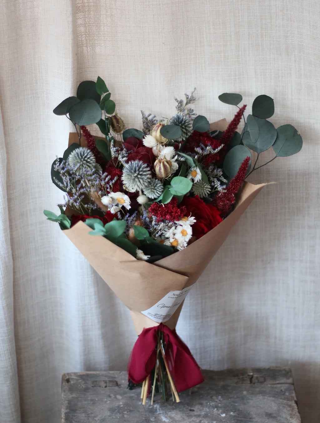 Bouquet of flowers wrapped in brown paper with a red ribbon on a textured surface