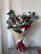 Bouquet of flowers wrapped in brown paper with a red ribbon on a textured surface