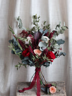 Bouquet of flowers with red, pink, and green colors on a textured surface